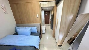 A modern hotel room with a bed, a flat-screen TV, and a wooden wardrobe. - Kathy’s Crib 11th flr pool view Shell Residences (Pasay City)