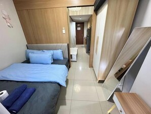 Una habitación de hotel moderna con una cama, un televisor de pantalla plana y un armario de madera.