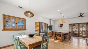A spacious kitchen with wooden cabinetry, a central island, and a large window offering a view of the outdoors. - Desert oasis with hot water  outdoor soaking tubs (Joshua Tree)