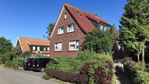 Ein zweistöckiges Backsteinhaus mit rotem Dach, einer Auffahrt und einem schwarzen Auto, das davor geparkt ist.