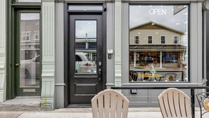 Une devanture de magasin avec une porte noire et une grande vitrine donnant sur un bâtiment situé de l’autre côté de la rue.