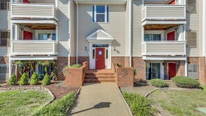A multi-story residential building with a central entrance, brick steps, and small front yard landscaping.
