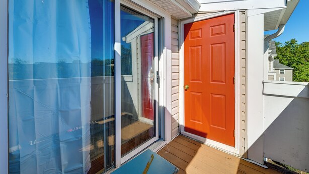 A house with a red door, a sliding glass door, and a wooden deck.