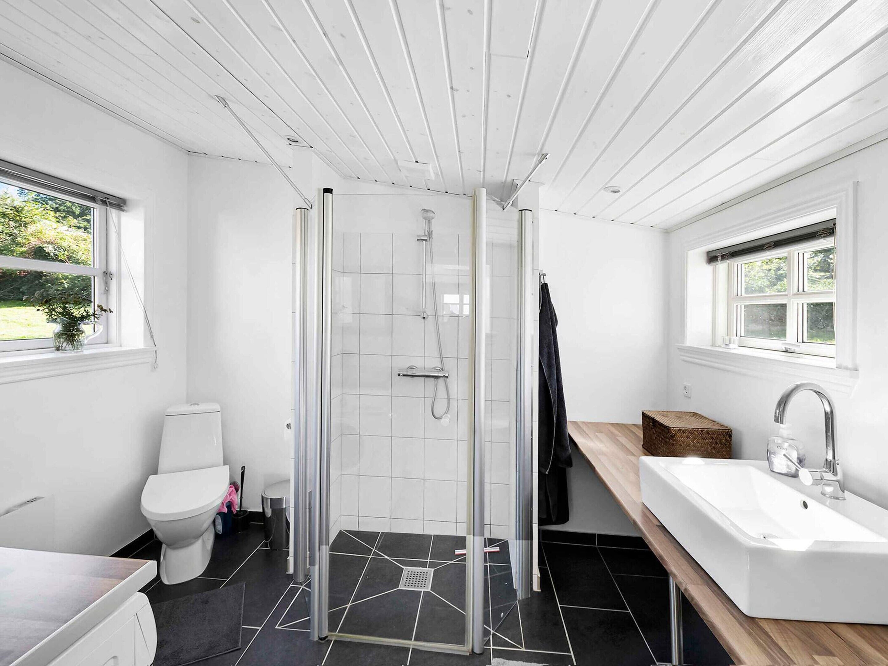 A modern bathroom with a shower, toilet, and sink.