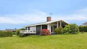 A modern house with a covered porch, a chimney, and a well-maintained lawn. - 5 Star Holiday Home in Bogense (Bogense)