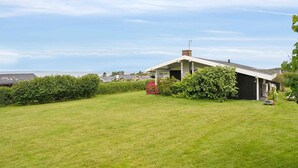A house with a covered porch, a lawn, and a view of the sea. - 5 Star Holiday Home in Bogense (Bogense)
