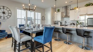 A modern kitchen with a dining area, featuring a large clock, pendant lights, and a bar area with stools. - 2 Mi to Zoo Atlanta: Modern Townhome w/ Balcony (Atlanta)