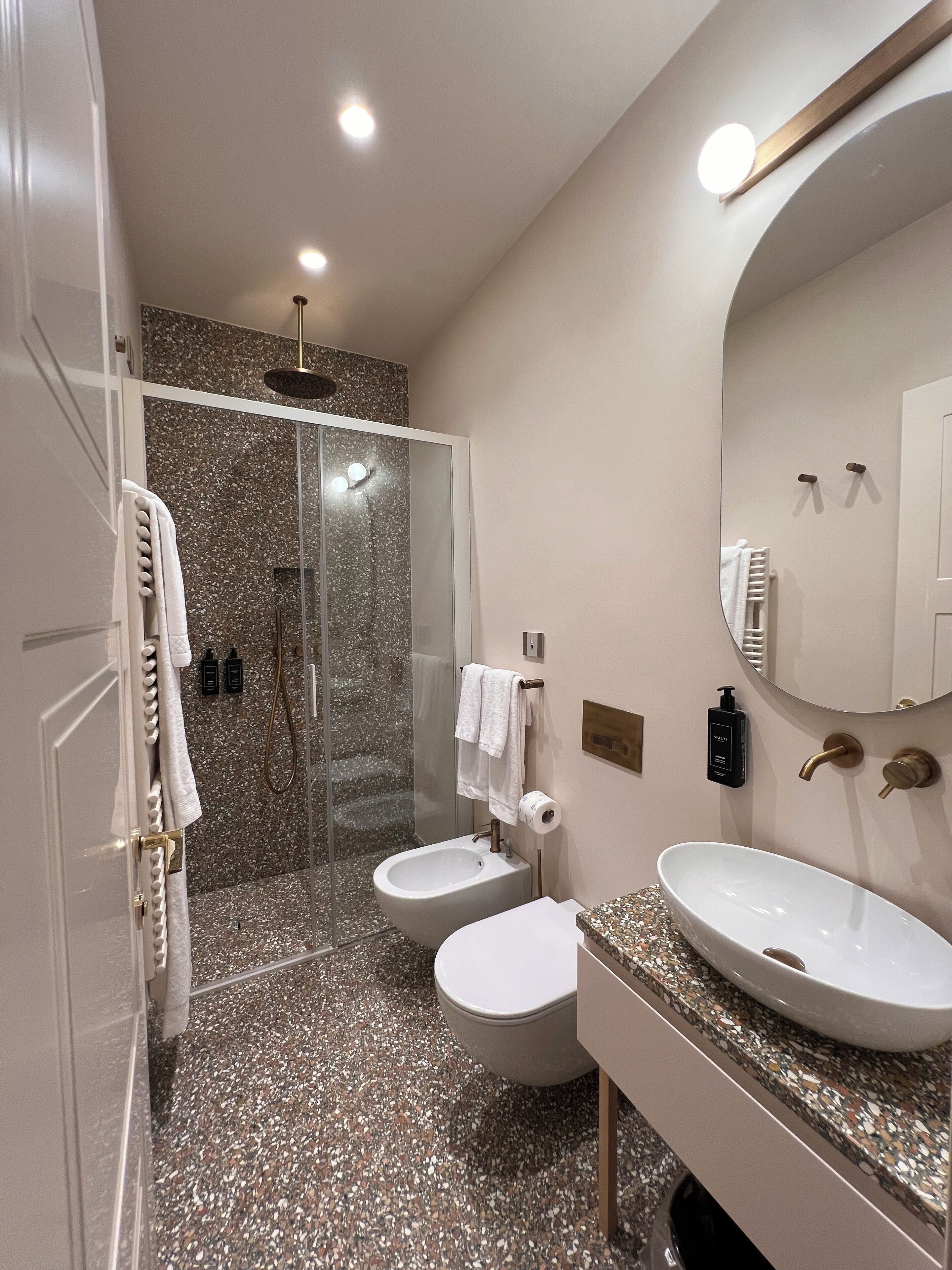 A modern bathroom with a shower, two toilets, a sink, and a large mirror.