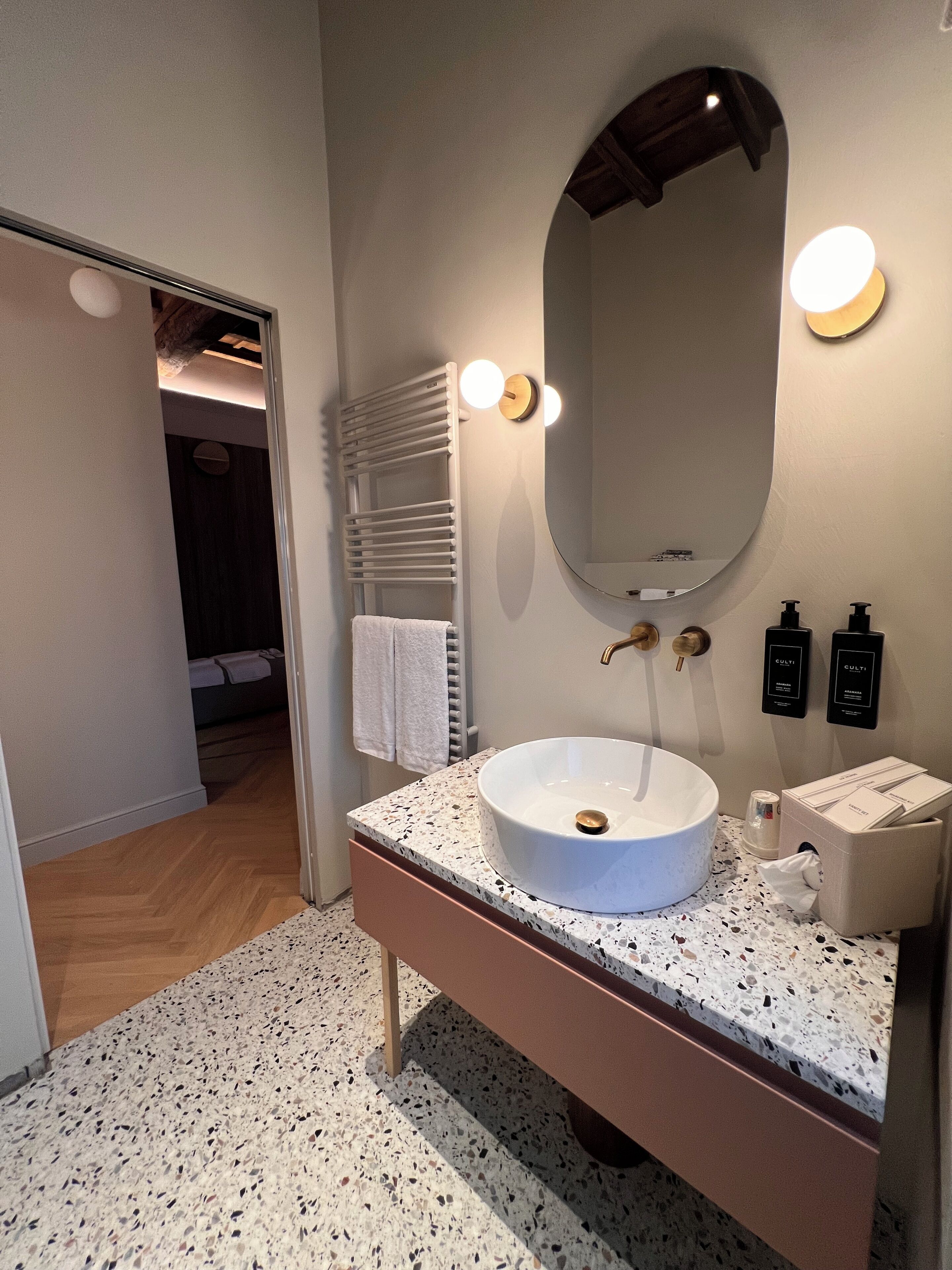 A modern bathroom with a freestanding sink, a large mirror, and a towel rack.