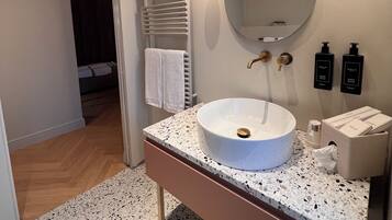 A modern bathroom with a freestanding sink, a large mirror, and a towel rack.