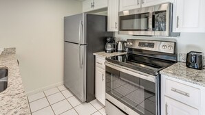 A compact kitchen with white cabinets, a stainless steel refrigerator, a microwave, an oven, and a sink. - Gateway to Orlando Theme Parks! Home w/ Large Yard (Winter Park)
