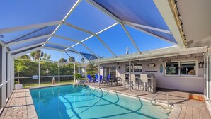 A covered swimming pool with a patio area, lounge chairs, and a bar. - Waterfront Home w/ Boat Dock & Bar in N Fort Myers (North Fort Myers)