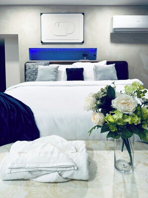 Una habitación de hotel moderna con una cama bien tendida, un jarrón de flores y una toalla sobre la mesa.