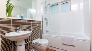 A modern bathroom with a white sink, toilet, and bathtub. - Marina View Apartment (Swansea)