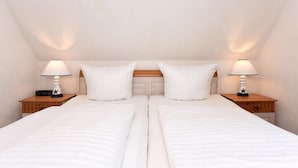 Une chambre double avec deux lits, chacun étant équipé d’une table de chevet et d’une lampe.