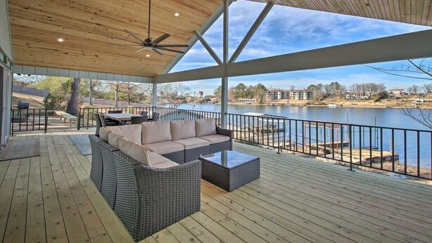 A covered outdoor deck with a sofa and coffee table, overlooking a lake. - Waterfront Getaway on Lake Hamilton (Lake Hamilton)