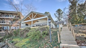 A building with a covered outdoor area, a staircase, and a view of a residential building in the background. - Waterfront Getaway on Lake Hamilton (Lake Hamilton)