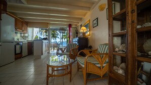 A spacious living area with wicker furniture, a glass coffee table, and a view of the ocean.