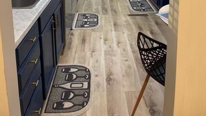 Eine moderne Küche mit weißen Schränken, einem schwarzen Kühlschrank und Holzboden.
