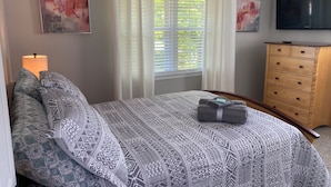 Ein Schlafzimmer mit einem Bett, einem Schminktisch, einem Fernseher und zwei Bildern.