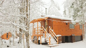 Een houten chalet met een overdekte veranda en een trap naar de ingang.