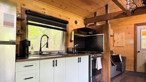 Een moderne keuken met witte kastjes, een zwarte kraan en een groot raam.