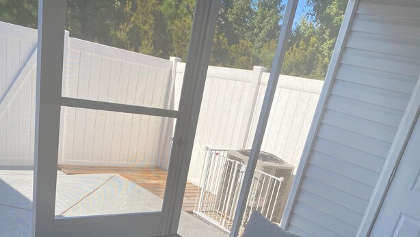 Ein überdachter Patio-Bereich mit Holztisch und Korbmöbeln.