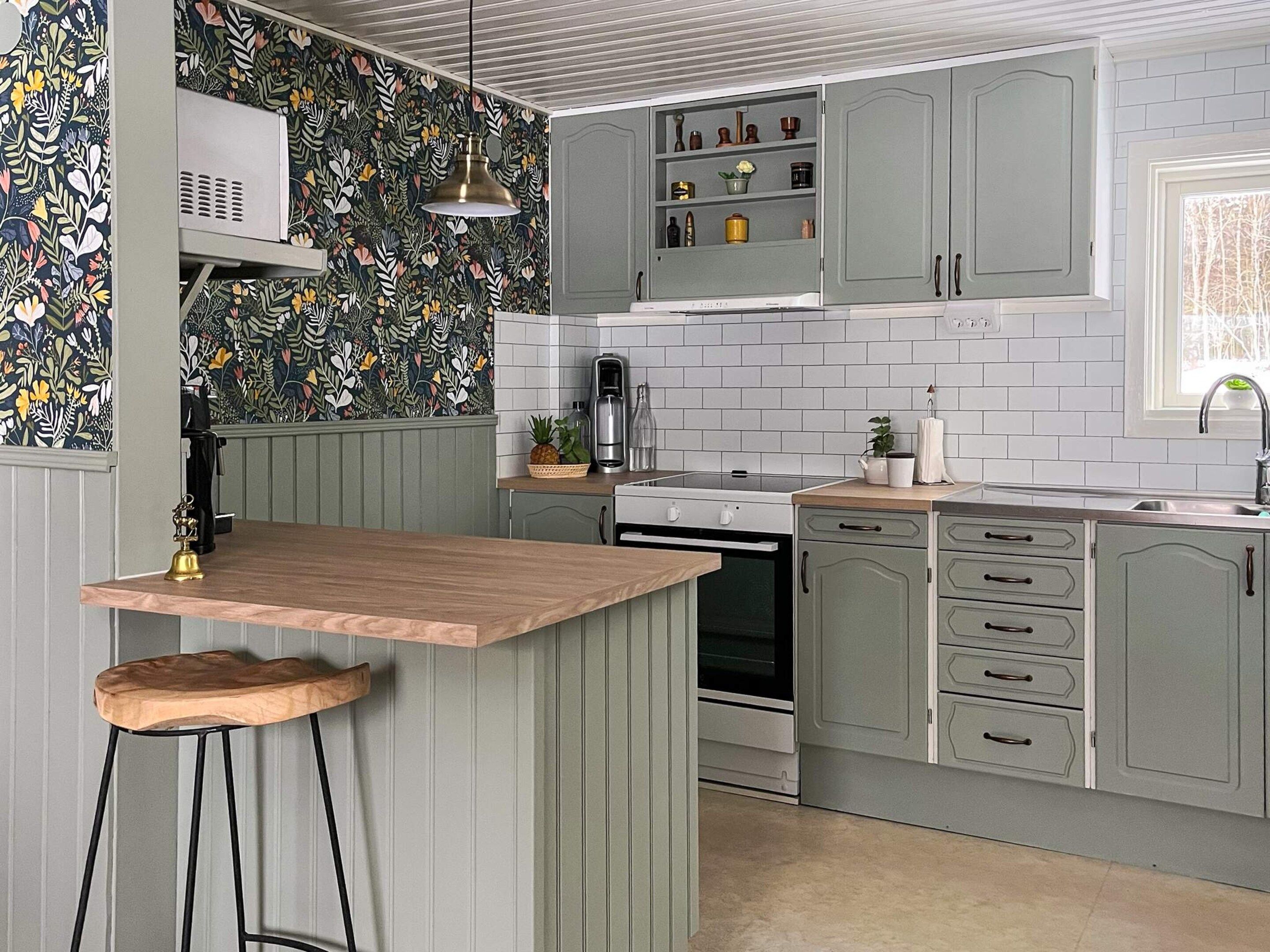 A kitchen with a wooden island, grey cabinets, and a patterned backsplash.