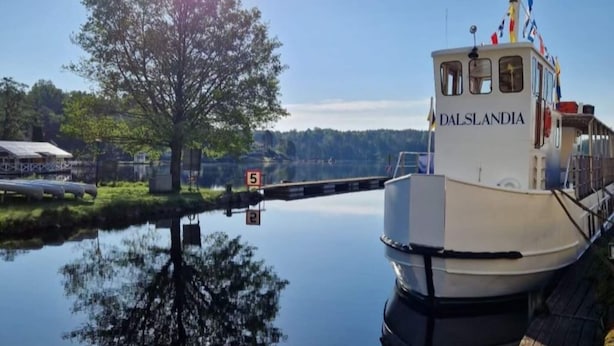 A boat named 'DALSLANDIA' docked at a calm water body with a clear sky and a large tree in the background. - 4 Star Holiday Home in Bralanda (Bralanda)