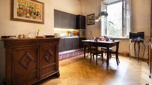 Una cocina con armarios de madera, una mesa de comedor con sillas, una alfombra y una ventana con luz natural.