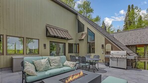 An outdoor patio with a sofa, chairs, a fire pit, and a grill area. - The Silos by Snowmass Vacations (Snowmass Village)