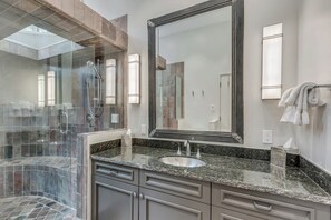 A modern bathroom with a glass-enclosed shower, a large mirror, granite countertops, and a sink. - The Silos by Snowmass Vacations (Snowmass Village)
