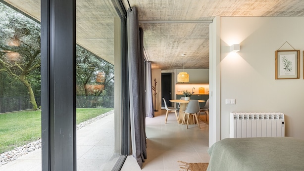 A modern bedroom with a large window, a bed, and a view of a dining area. - Villa 243 - Charming Villa in a peaceful area (Orbacém)
