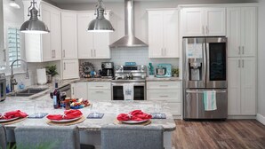 A modern kitchen with white cabinets, stainless steel appliances, and a marble island.
