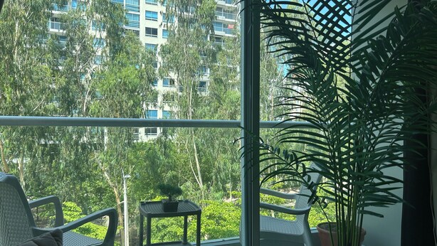 A balcony with a view of a high-rise building, a potted plant, and outdoor furniture. - Charming 2-bedroom apartment in delightful Barranquilla with AC (Barranquilla)