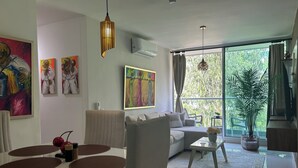 A modern living room with a dining area, large windows, and artwork on the walls. - Charming 2-bedroom apartment in delightful Barranquilla with AC (Barranquilla)