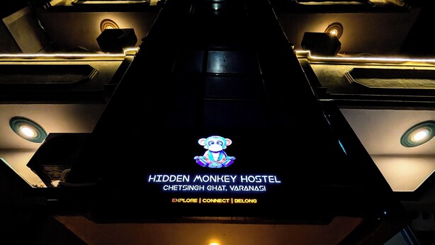 A building with a sign reading "Hidden Monkey Hostel" and a monkey illustration. - Hidden Monkey Hostel Chet Singh Ghat (Varanasi)