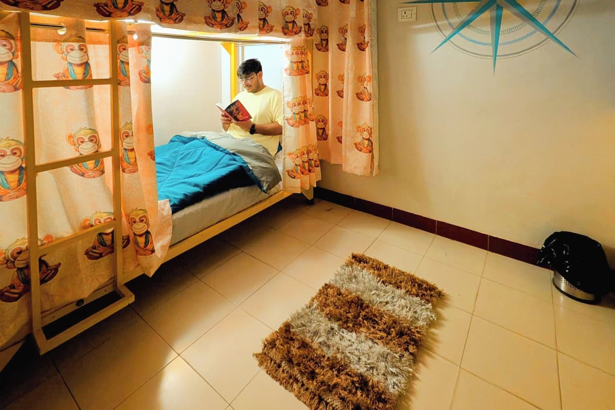 A room with a bunk bed, a patterned curtain, a compass wall decoration, and a tiled floor.