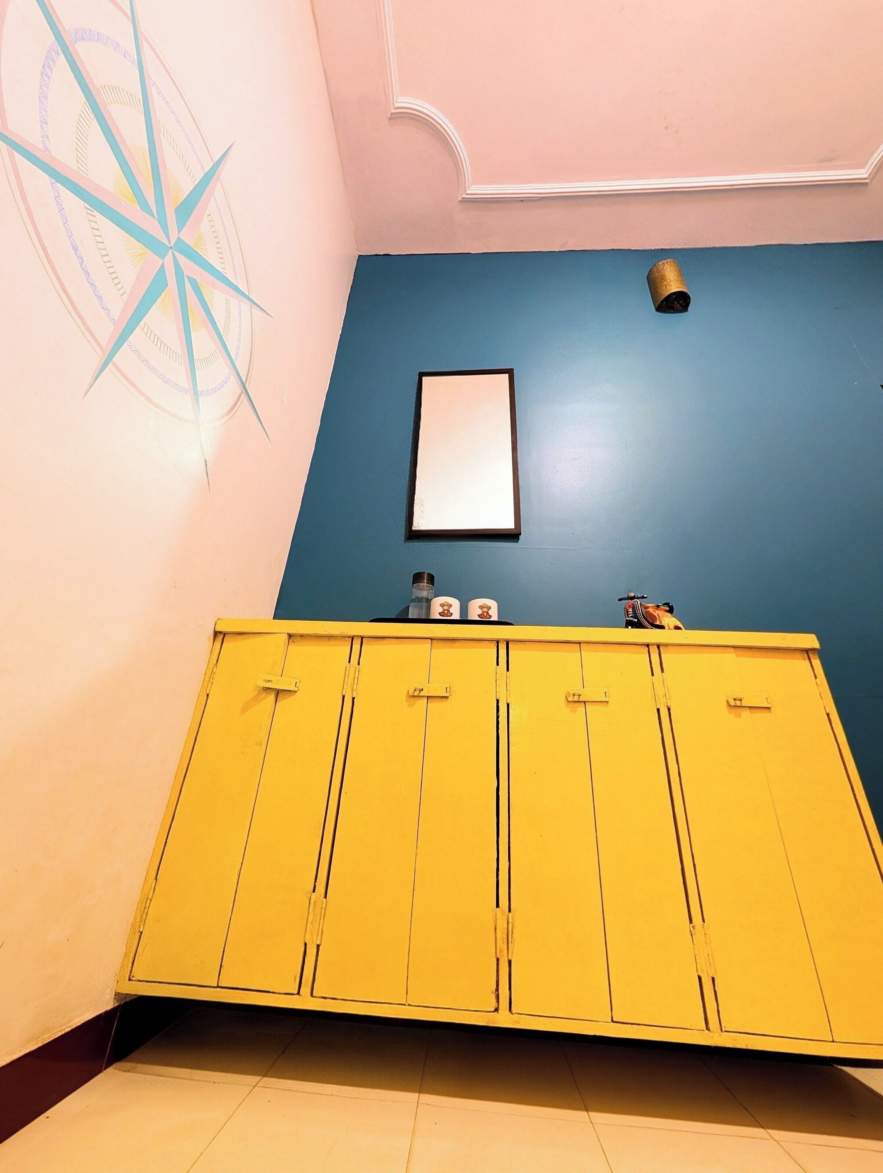 A room with a yellow cabinet, a blue wall, and a compass decoration.