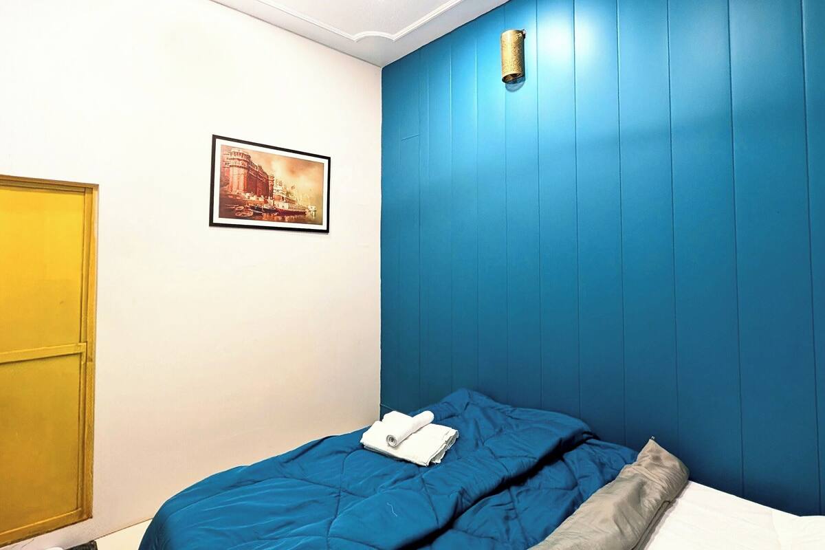 A bedroom with a bed, a ceiling fan, a picture on the wall, and a door.