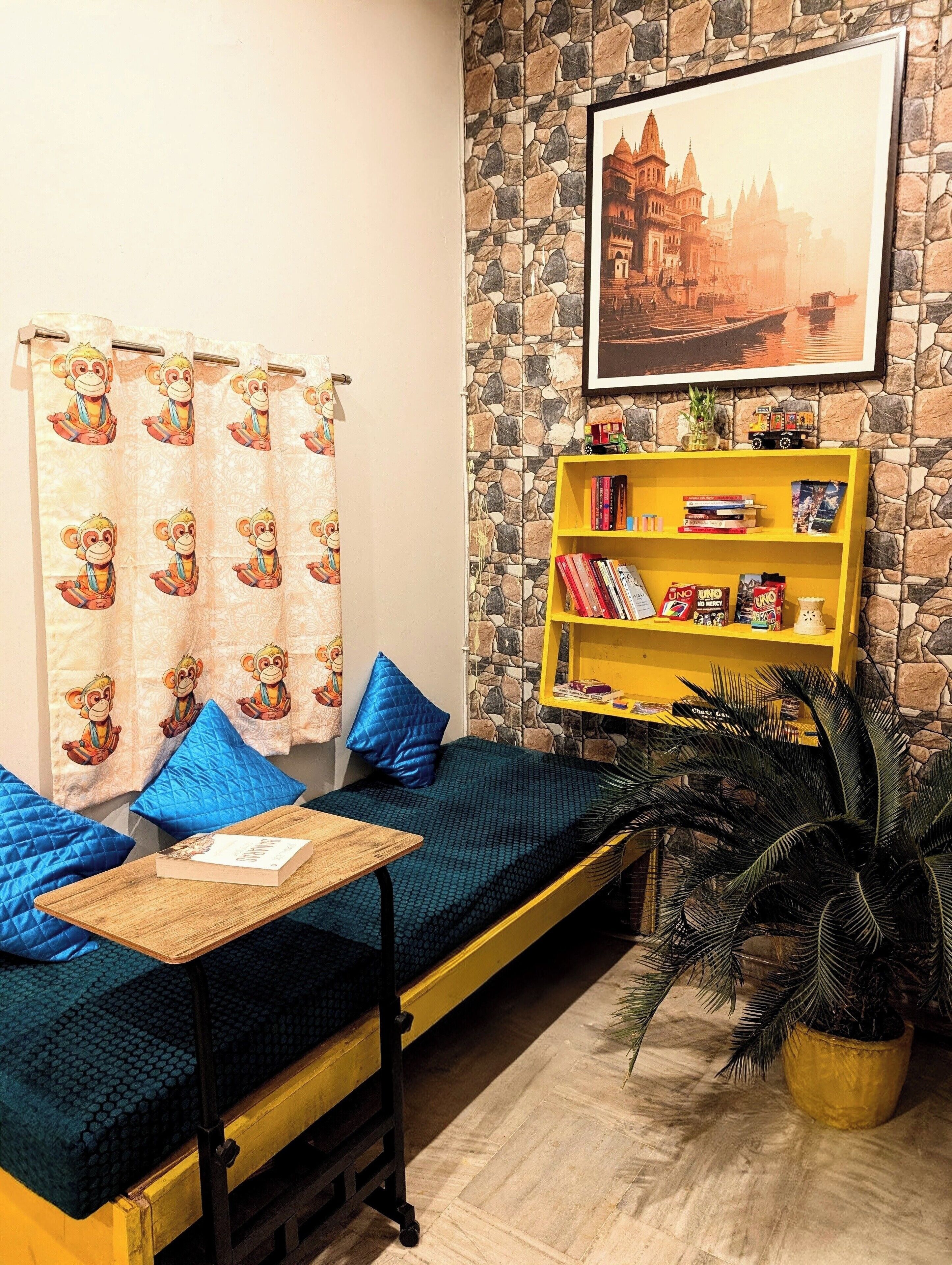 A cozy room with a sofa bed, a small table, a bookshelf, and a potted plant.