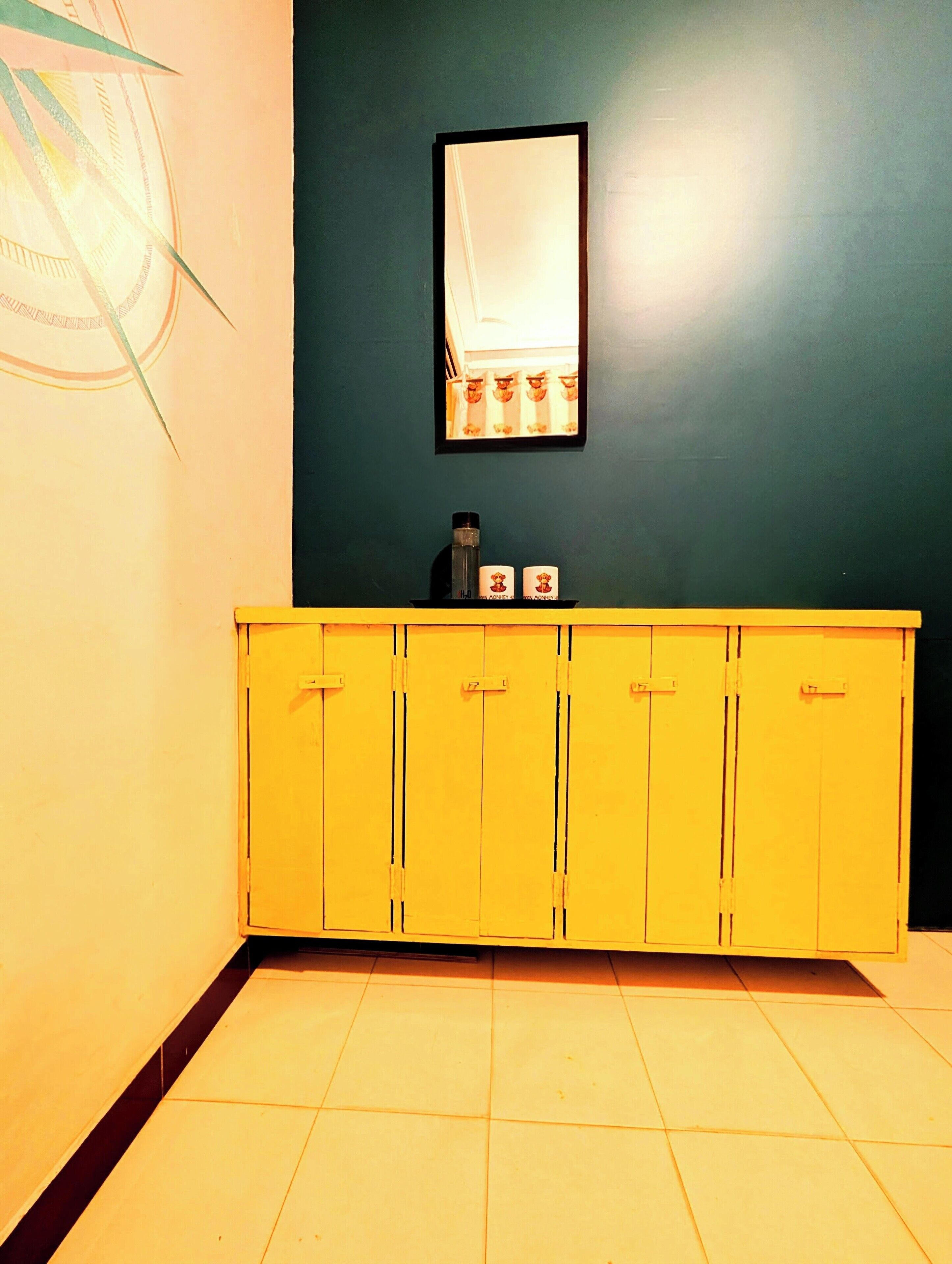 A bathroom with a yellow cabinet, a mirror, and a towel rack.