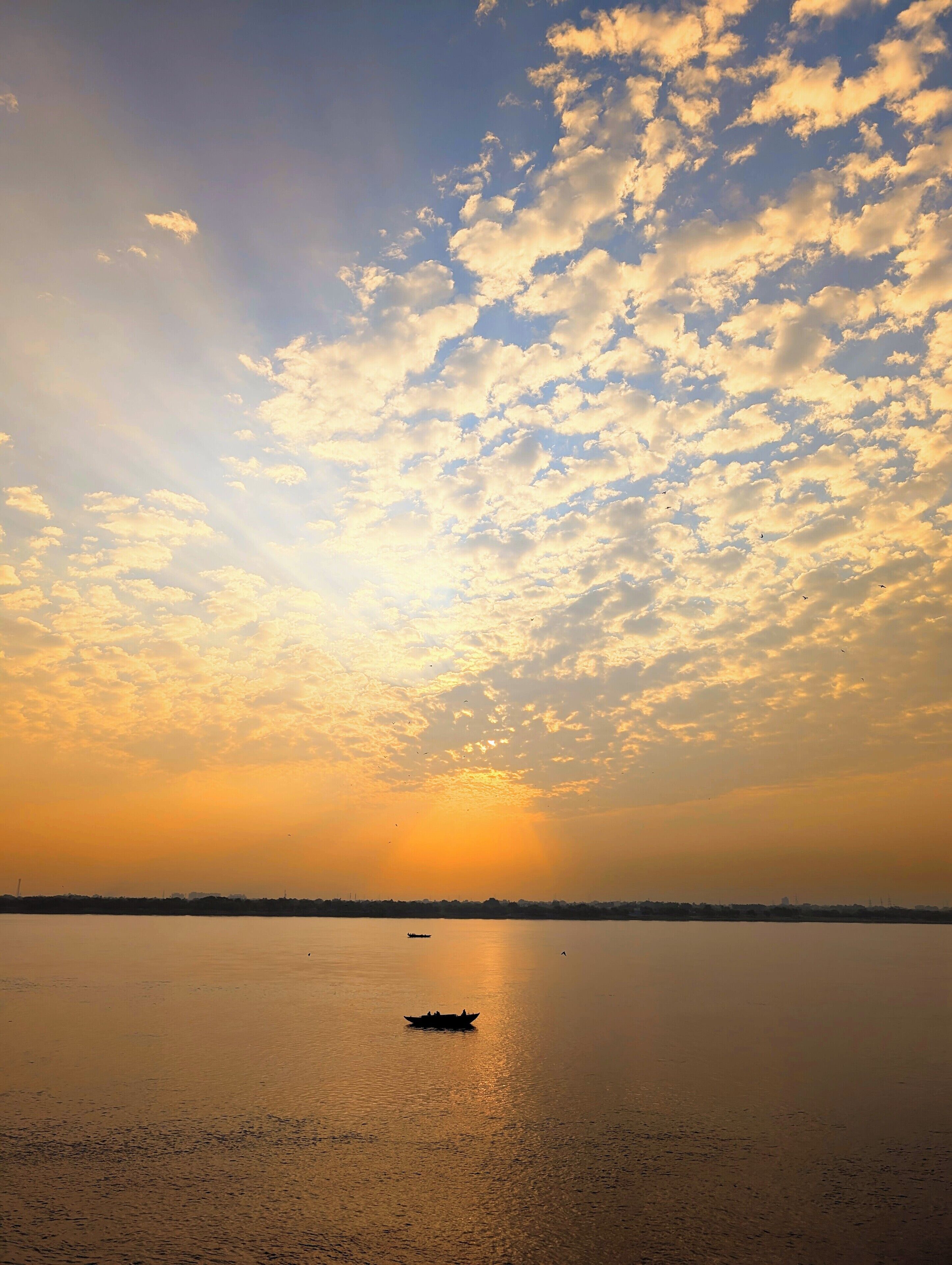 Un plan d’eau paisible, avec un bateau au premier plan et un coucher de soleil en arrière-plan.