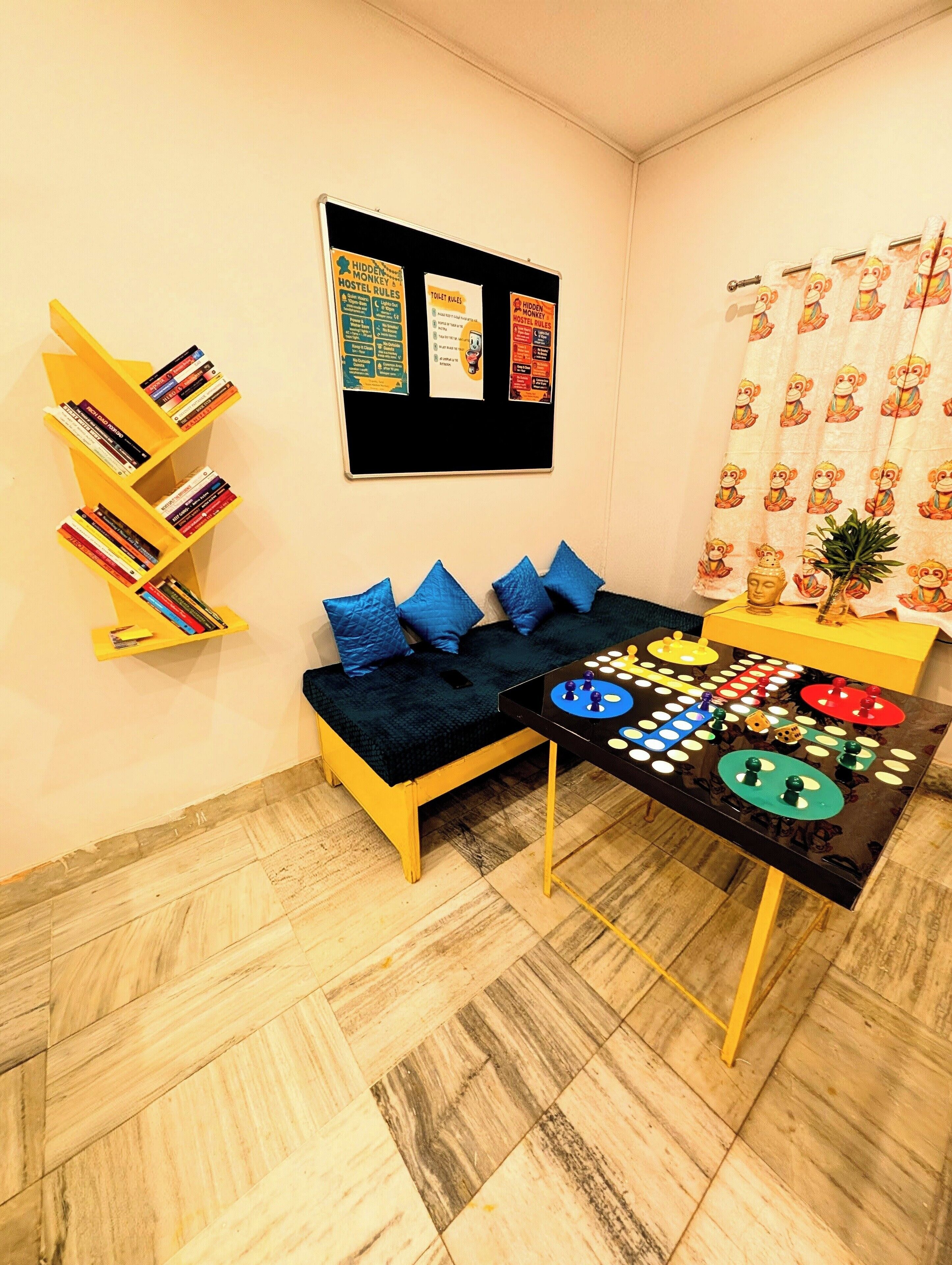 Une pièce confortable avec un canapé, une bibliothèque, un tableau d’affichage et une table sur laquelle est posé un jeu de société.