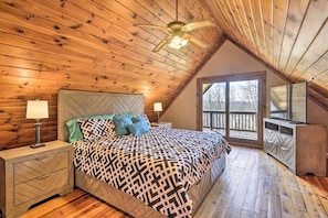 A bedroom with a sloped ceiling, a bed with patterned bedding, bedside lamps, and a dresser.
