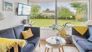 A modern living room with a large window, a flat-screen TV, and two sofas.