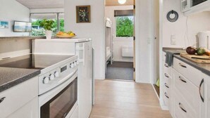 A modern kitchen with white cabinetry, a built-in oven, and a countertop with a fruit bowl.
