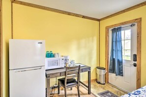 Quarto compacto com cozinha compacta, incluindo frigorífico, micro-ondas e máquina de café.