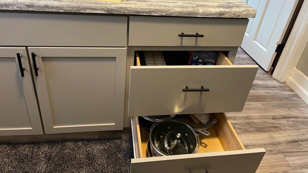 A kitchen with a sink, a coffee maker, and a drawer with kitchen utensils. - Quiet 3 Bedroom home Near downtown (Lansing)