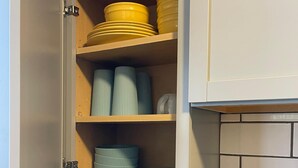 A kitchen with a built-in cabinet containing yellow plates, striped bowls, and a spice rack. - Quiet 3 Bedroom home Near downtown (Lansing)